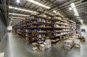 Warehouse racking in large industrial space. people working in warehouse