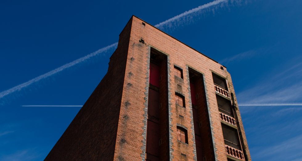 Old red brick warehouse. Liverpool docklands. Vapour trails.
